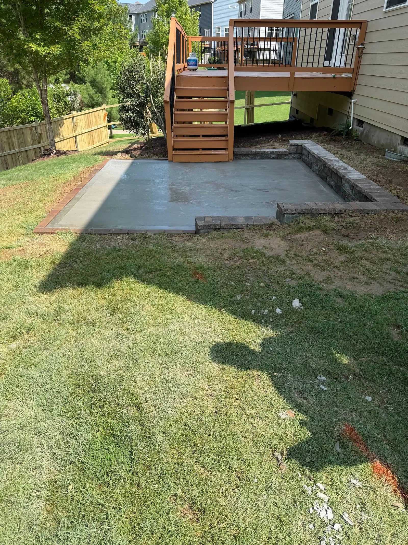 Concrete patio with stone retaining wall borders in residential backyard