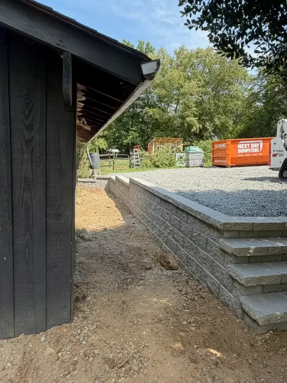 Concrete retaining wall with steps and gravel driveway base installation