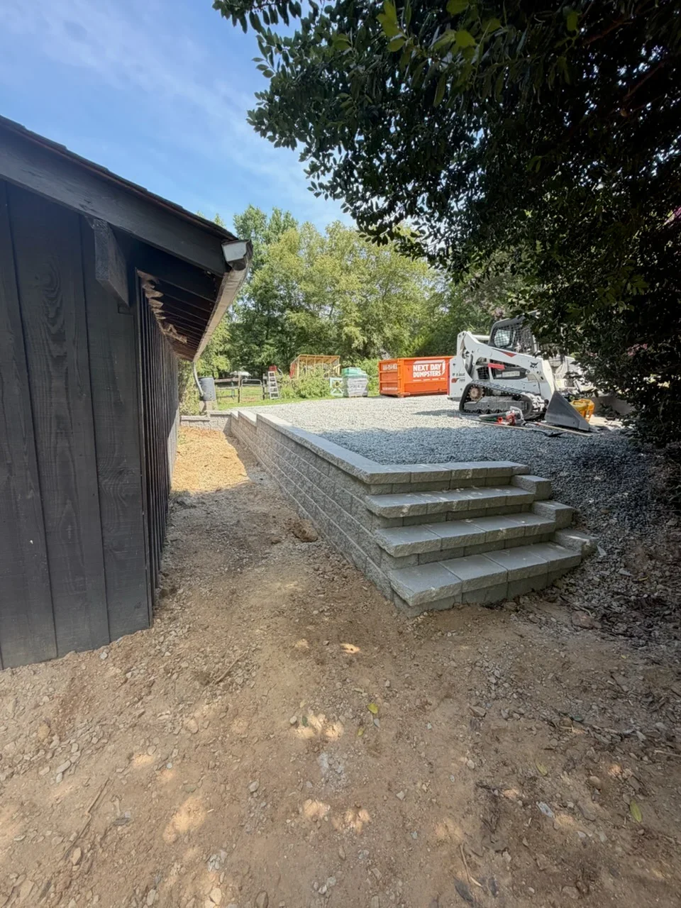 Stacked concrete block retaining wall with four steps and gravel base on residential property