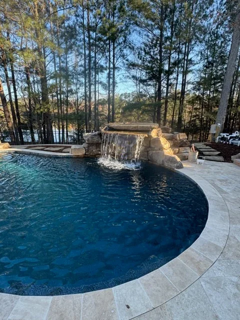 A finished custom inground pool in a Cary, NC backyard with surrounding patio space and mature landscaping. The pool is built to fit the lot and reflects the outdoor living style common across the Triangle region.